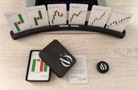 Vista cenital del soporte Oliver Velez con seis cartas de pie, la caja rígida abierta con la baraja dentro y el clicker.